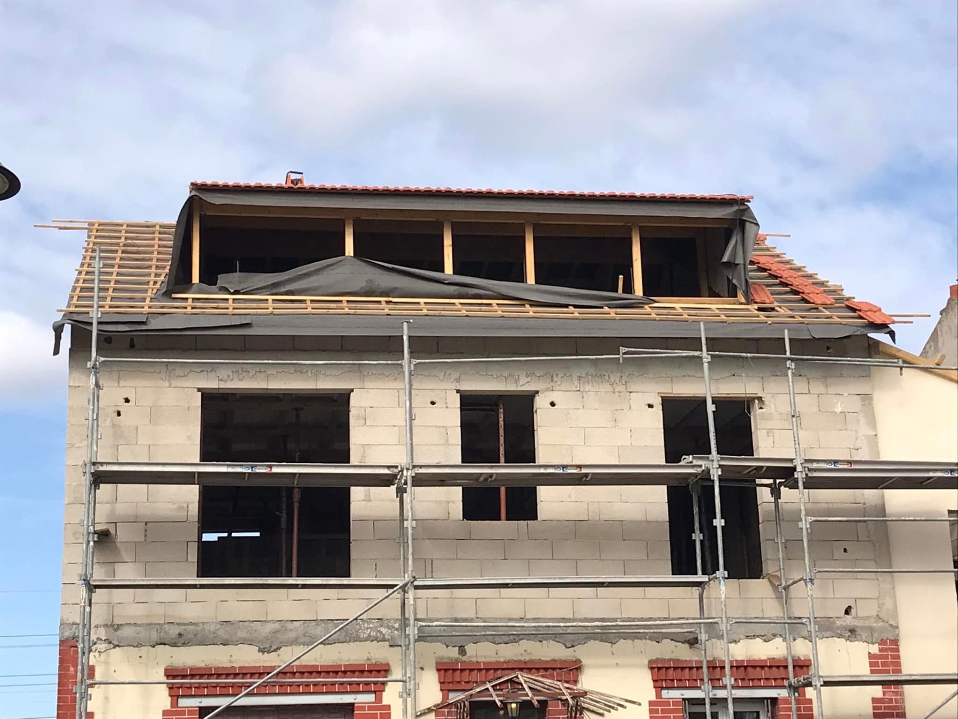 LUX RENOV — façade en cours de surélévation avec charpente bois et début de couverture tuiles