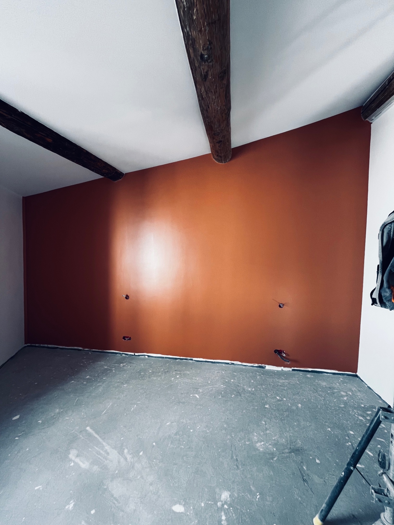 LUX RENOV — mur d'accent terracotta sous poutres apparentes dans une chambre