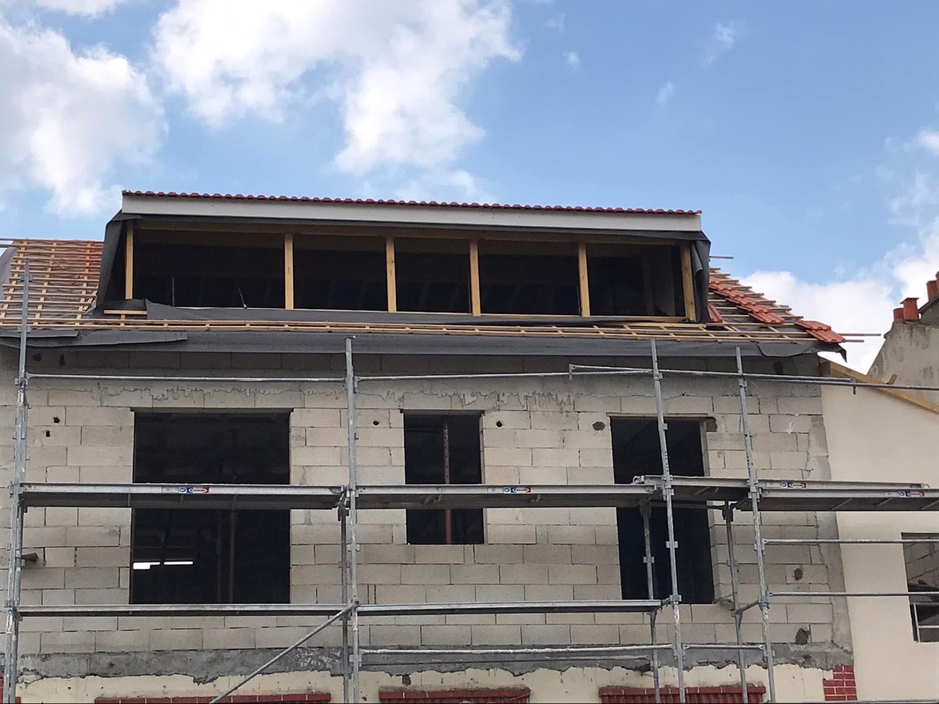 LUX RENOV — façade surélevée avec lucarne et début de pose des tuiles