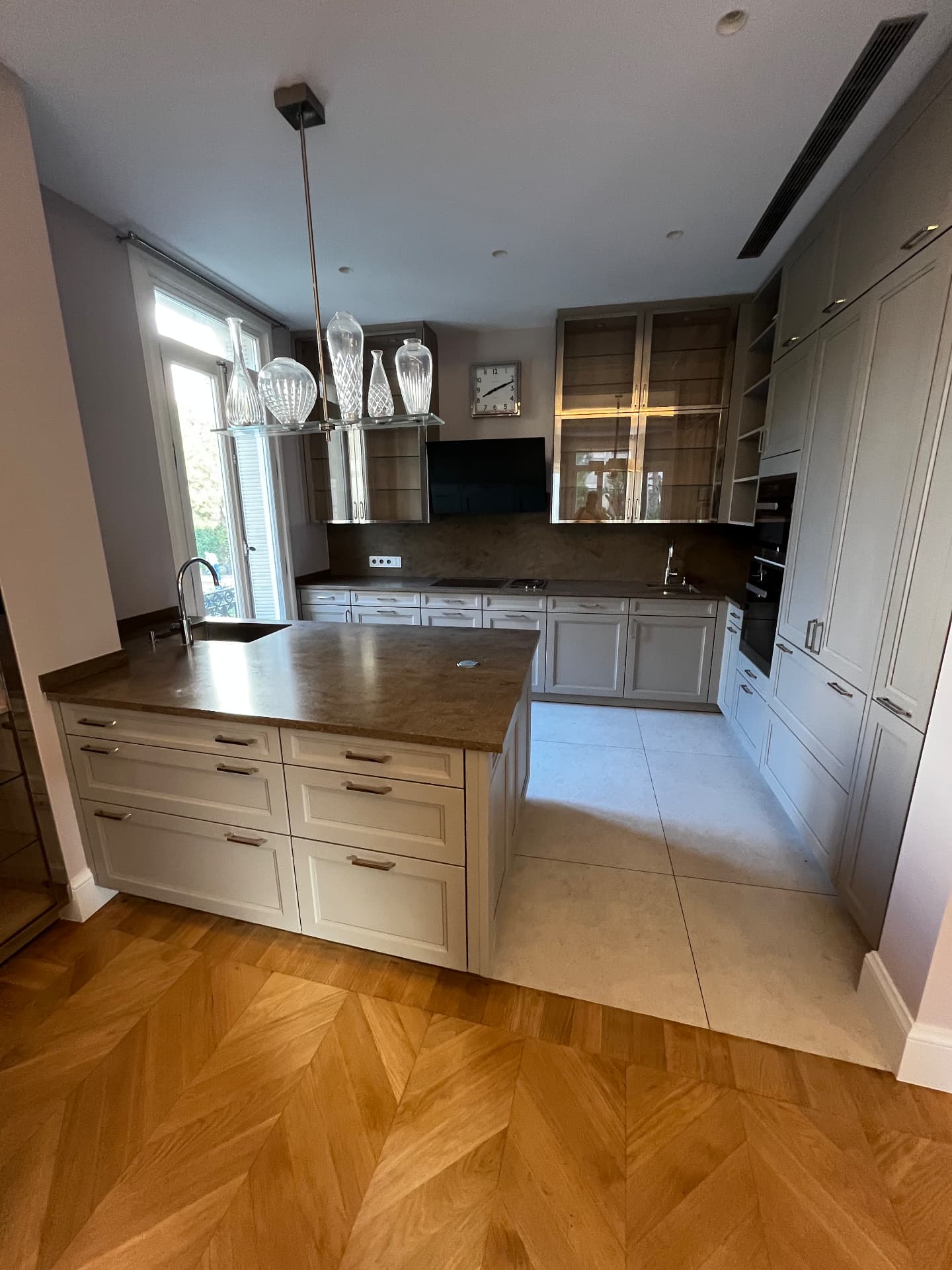LUX RENOV Monaco — cuisine sur mesure avec îlot, plan de travail en pierre et parquet point de Hongrie