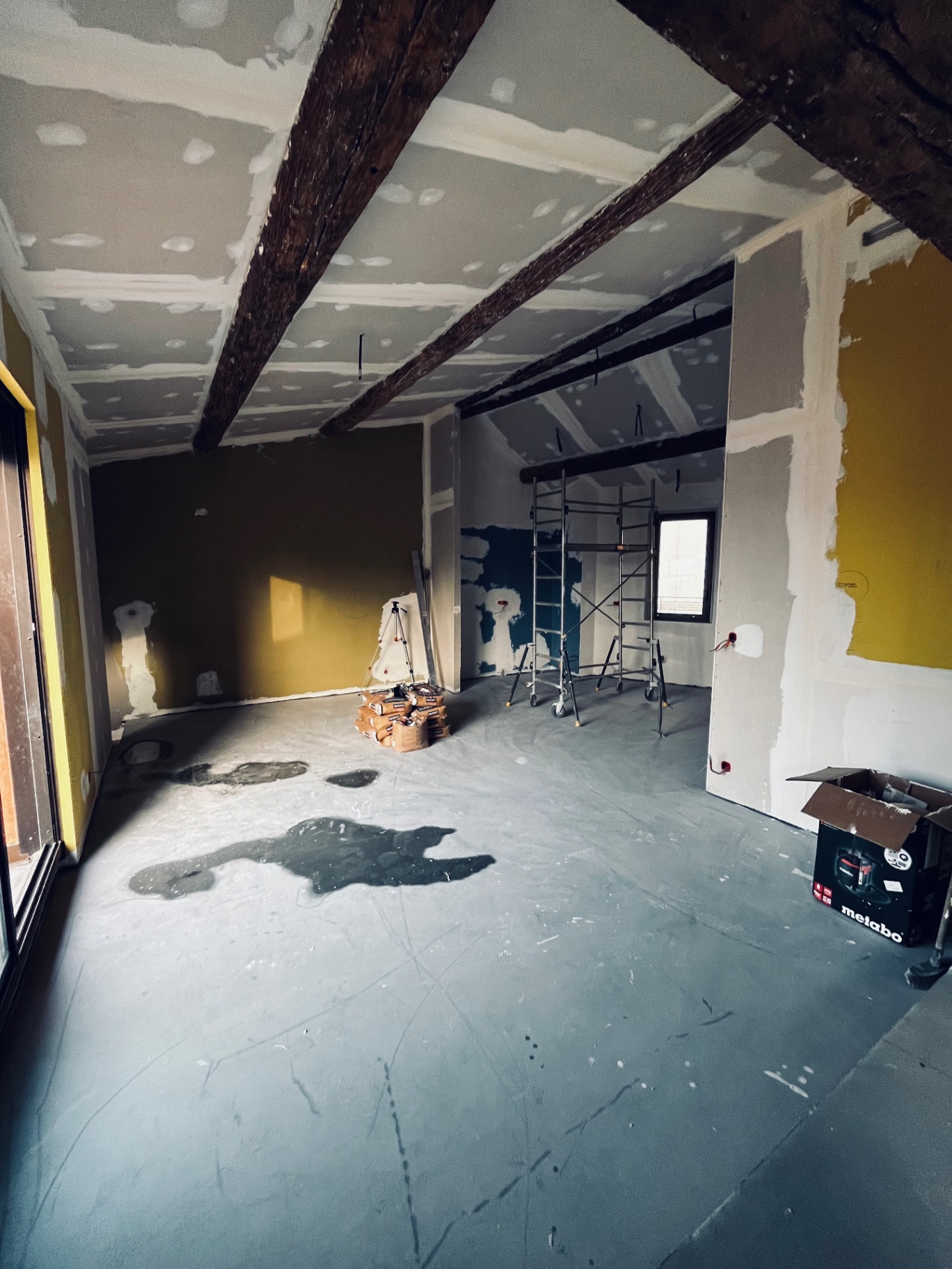 LUX RENOV — grande pièce de vie en cours de rénovation avec poutres apparentes et placo neuf