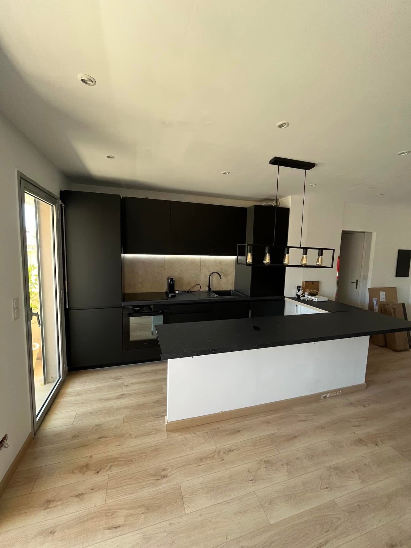 LUX RENOV — cuisine noire moderne livrée avec îlot central et parquet chêne