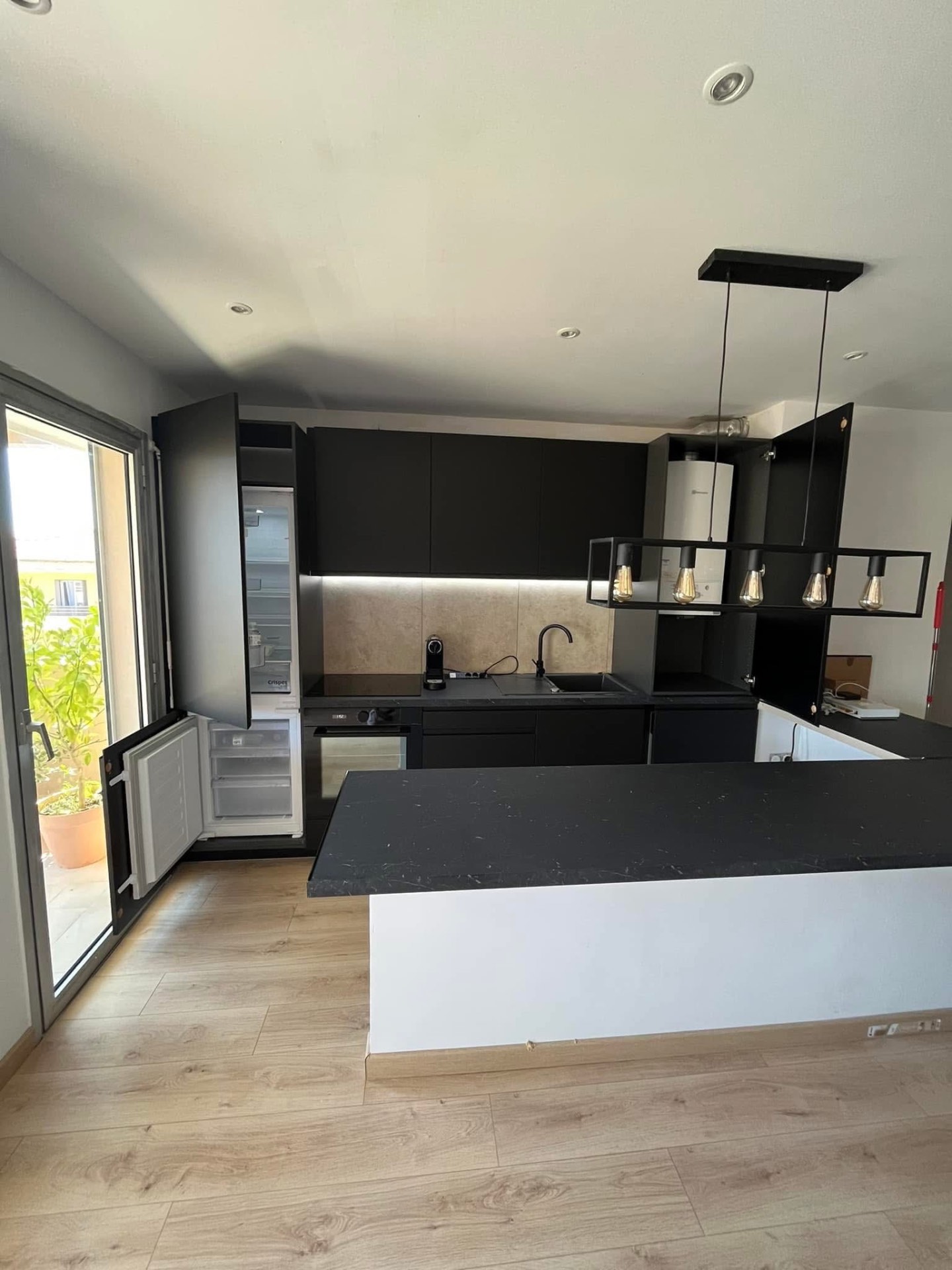 LUX RENOV — vue d'ensemble cuisine noire ouverte avec frigo encastré et LED