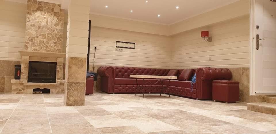 LUX RENOV — pool house aménagé avec canapé Chesterfield bordeaux et cheminée pierre