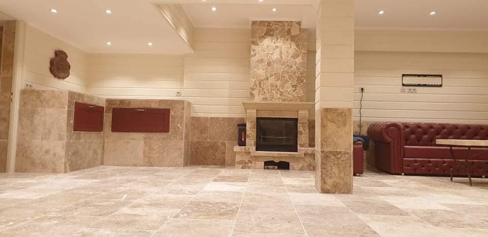 LUX RENOV — pool house livré : salon travertin avec cheminée centrale en pierre