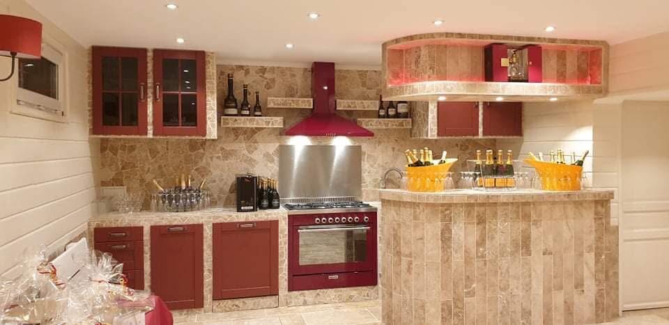 LUX RENOV — cuisine d'été finie avec piano de cuisson, hotte bordeaux et bar arrondi