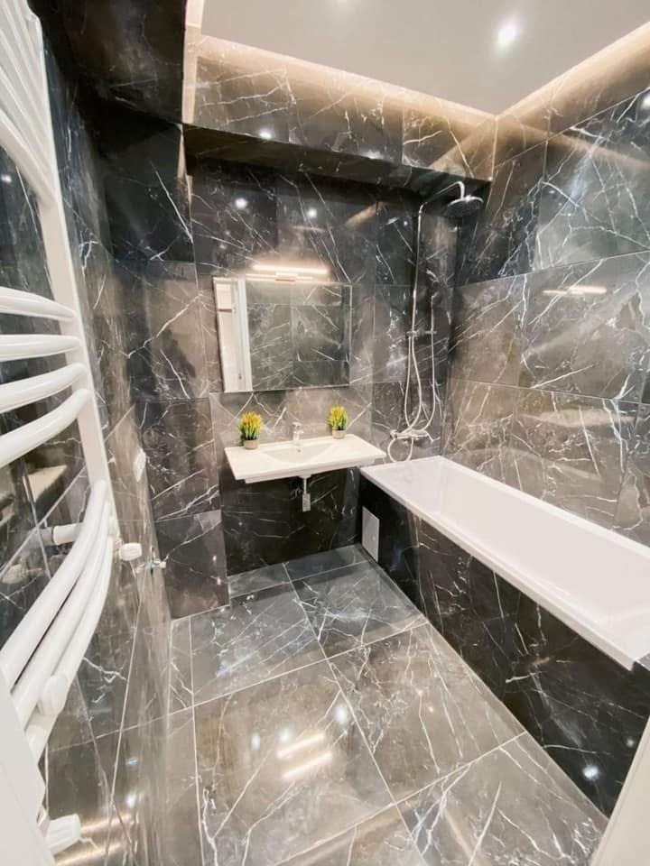 LUX RENOV — salle de bain marbre noir veiné avec baignoire et corniche LED